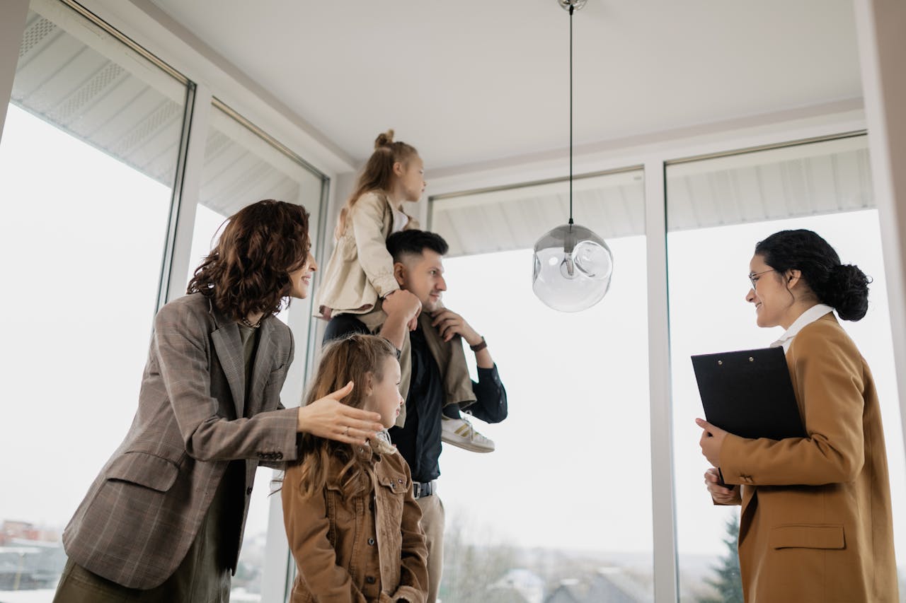A family with children excitedly tours a modern home guided by a real estate agent.